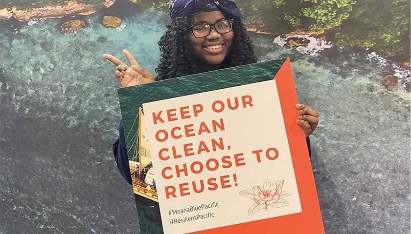 photo of girl with sign saying "keep our ocean, choose to reuse"