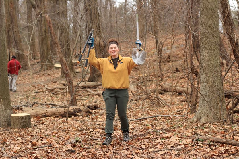 A woman holding a pair of scissors in the woods.