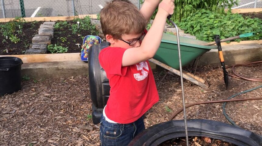 A child turning the compost bin looking for worms.