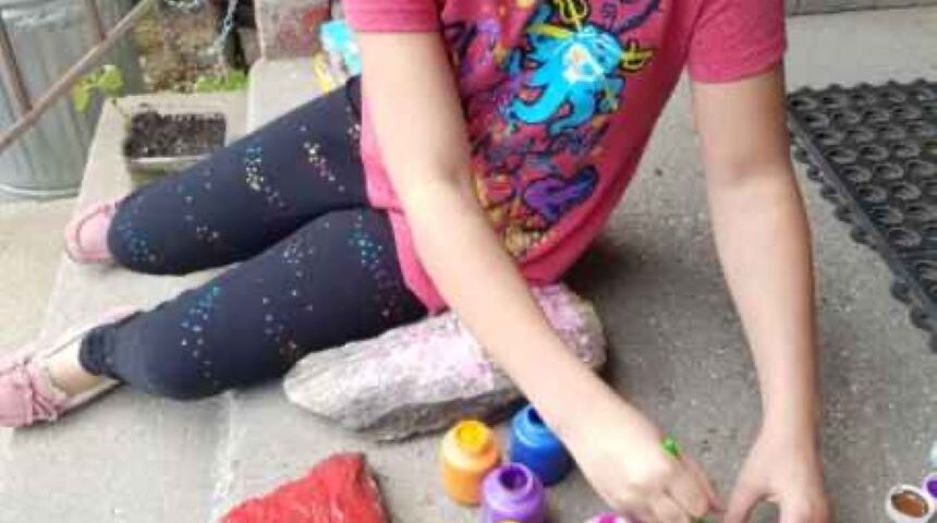 Girl painting a tulip on a rock.