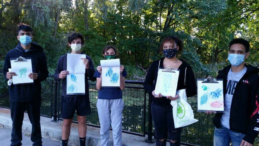 A group of people wearing masks holding up drawings.