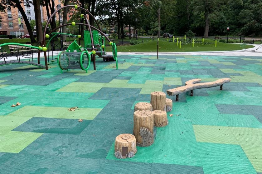 A green playground with benches and logs.