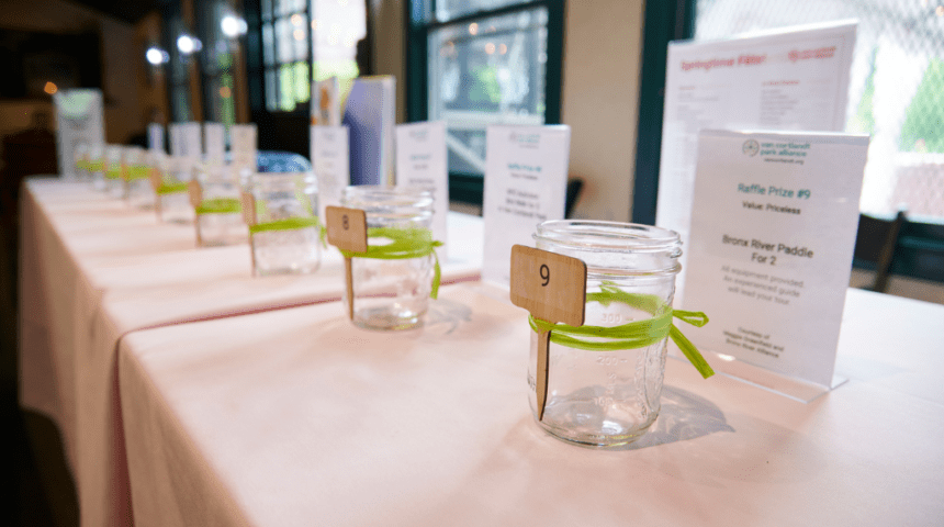 A table is lined with jars with green ribbons.