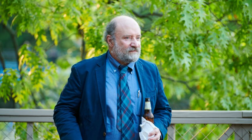 A man in a blue suit holding a bottle of beer.