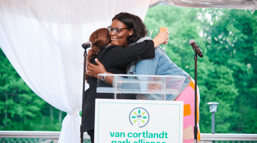 Two women hugging in front of a podium.