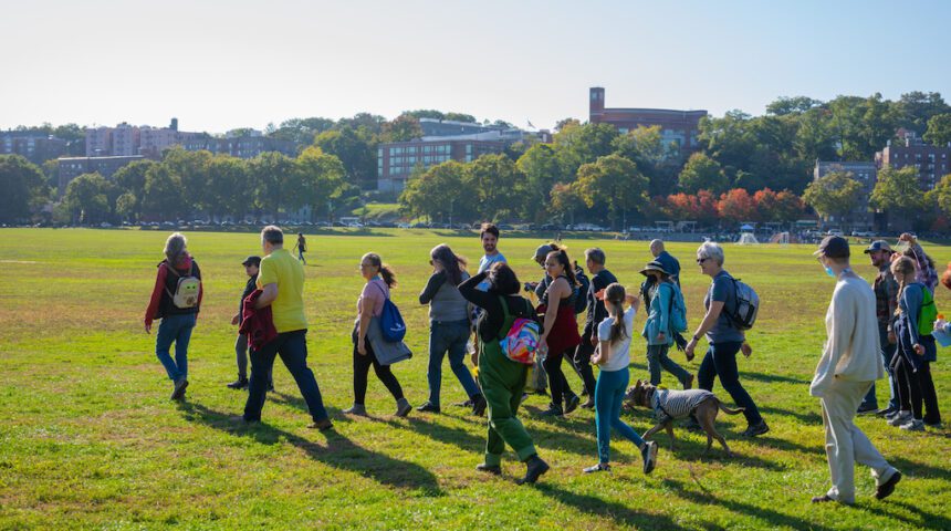 A group of people walking on a grassy field.