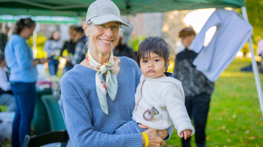 An older woman holding a baby at an outdoor event.