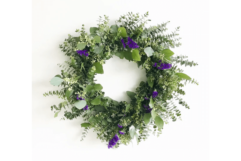A wreath with purple flowers and eucalyptus leaves.