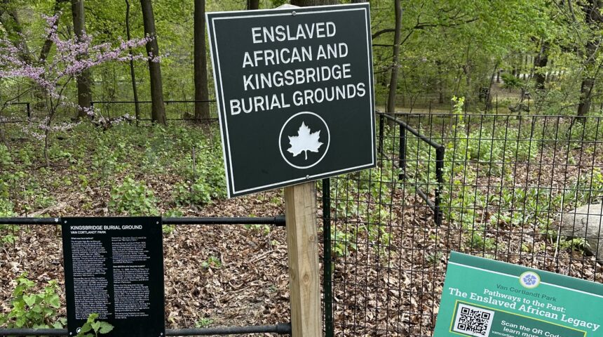 A sign on a fence in a wooded area.