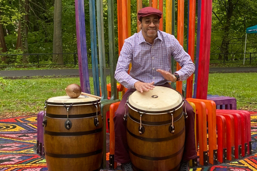 A man playing a conga drum in a park.