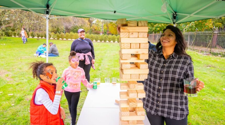 A group of people playing a game of jenga at a park.