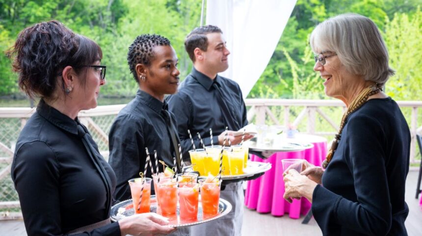 A group of people serving drinks at an outdoor event.