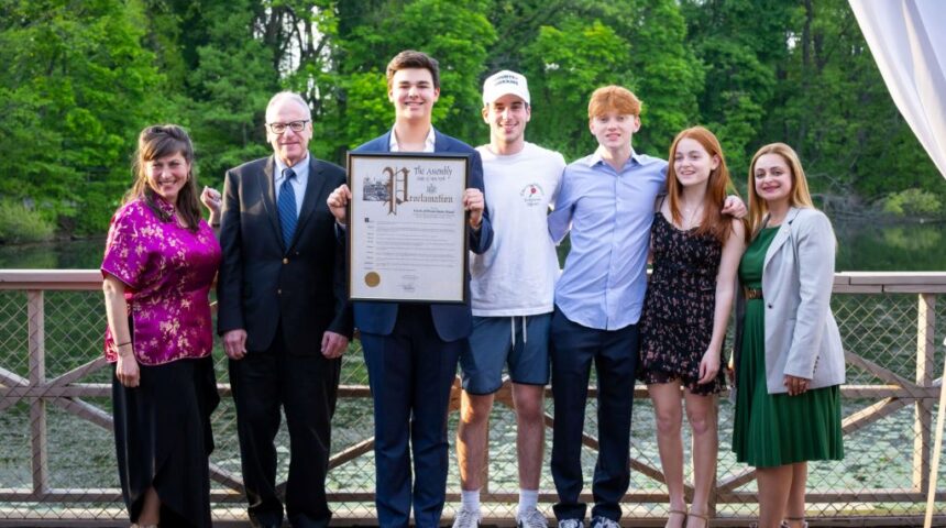 A group of people standing on a bridge holding a certificate.