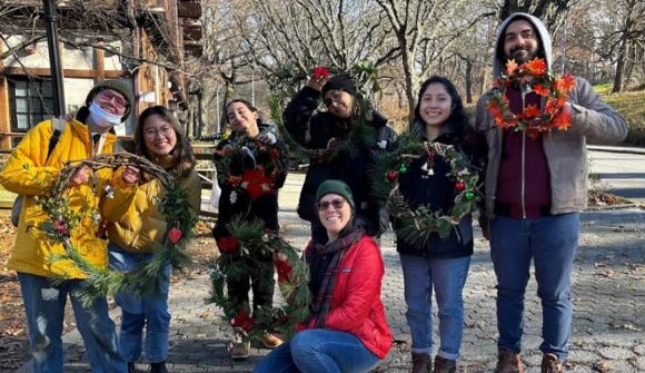 Seven people outside smiling and holding up wreaths that they made.