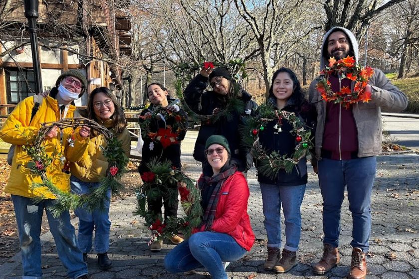 Seven people outside smiling and holding up wreaths that they made.