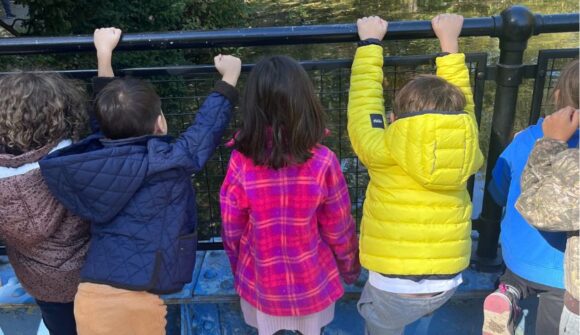 A group of kids looking through a fence at a pond.