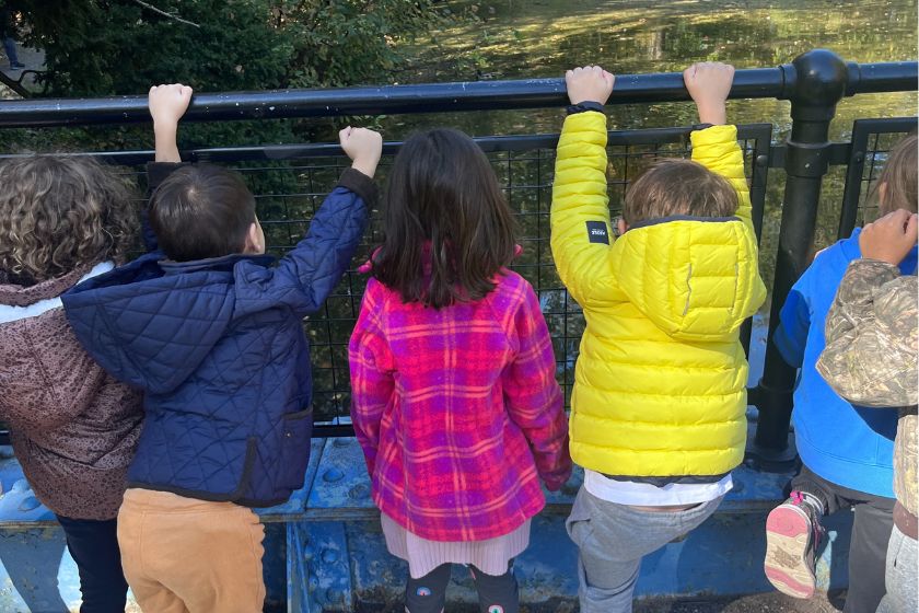 A group of kids looking through a fence at a pond.