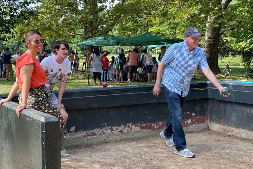 A man in a hat getting ready to throw a bocce ball with a woman and man watching.