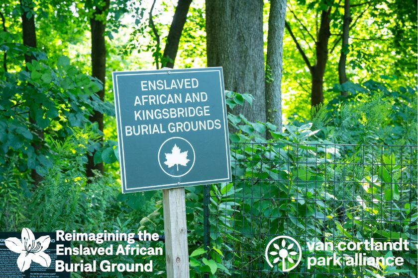 A picture of a green sign with white writing "Enslaved African and Kingsbridge Burial Ground" in front of trees.