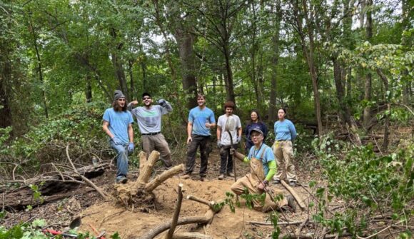 A happy group of people in the woods celebrating the work that they accomplished.