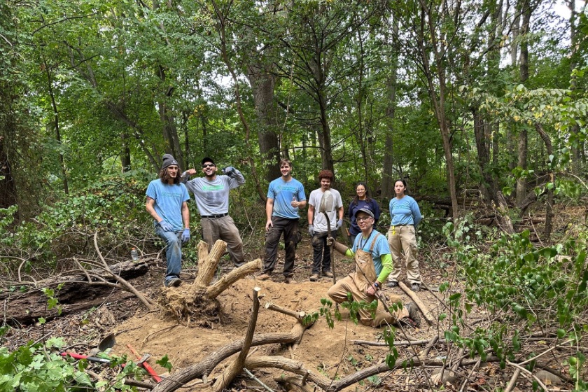A happy group of people in the woods celebrating the work that they accomplished.