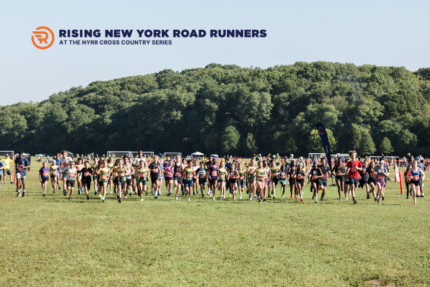A group of young people runing across a green grassy field with a hill of trees in the background.